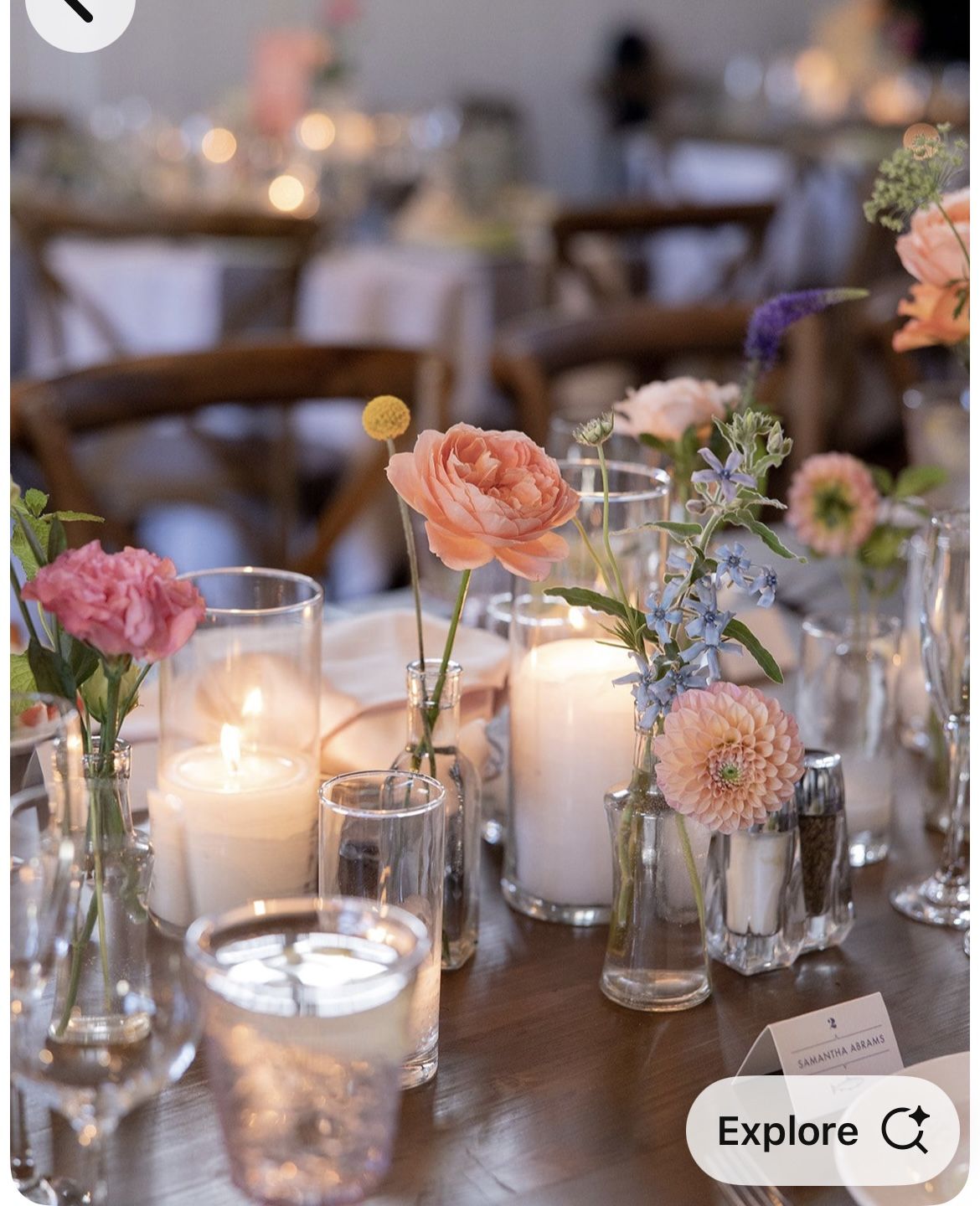 Dark wood table with scattered bud vases and white pillar candles in glass.