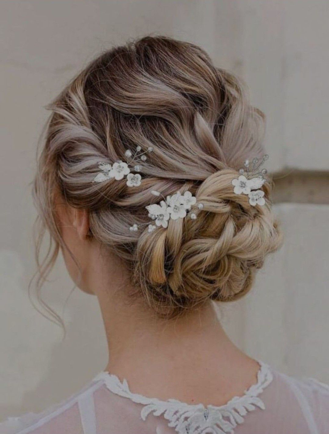 An intricately woven low bun with small white flower accessories on textured hair.