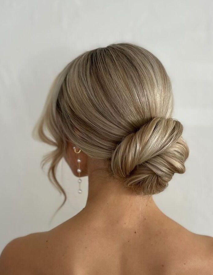 A smooth minimalist low bun with a wrapped base and elegant finish on blonde hair.
