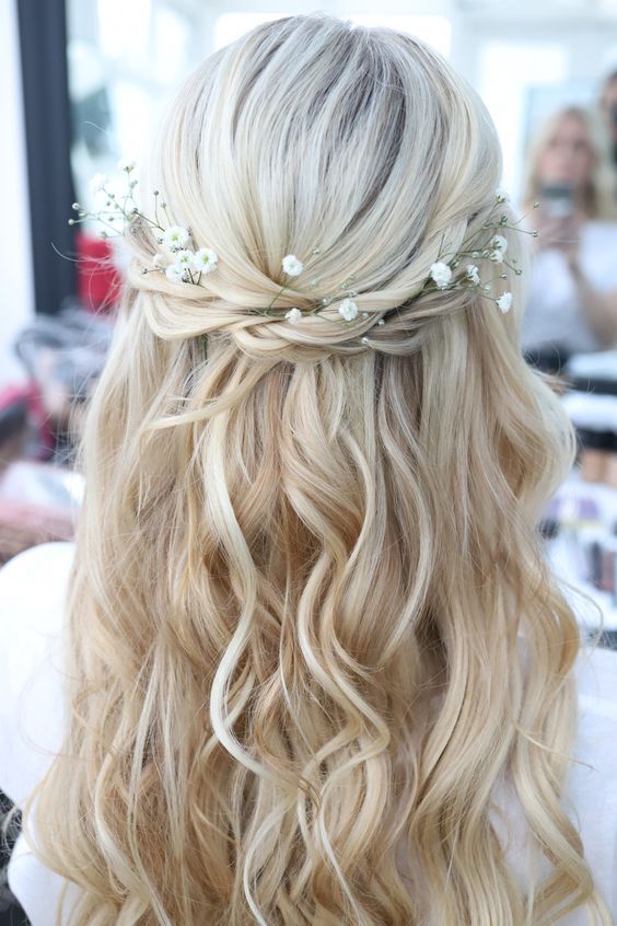 Twisted half-up hairstyle with soft curls and delicate baby’s breath flowers placed throughout for a light romantic finish