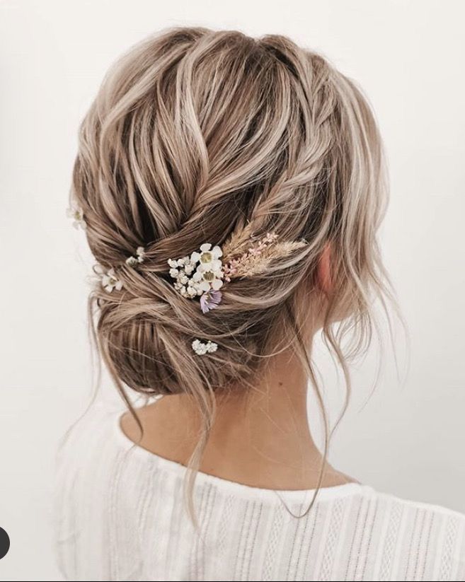 Textured updo with layered sections and soft floral details woven in, creating depth and interest from every angle