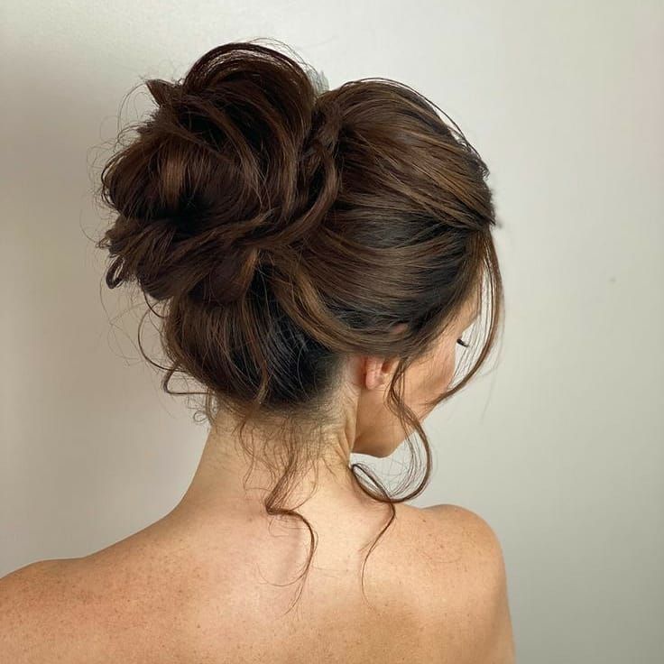 A voluminous dark bun hairstyle with soft texture and height, showcasing rich hair tones and a full, elegant shape