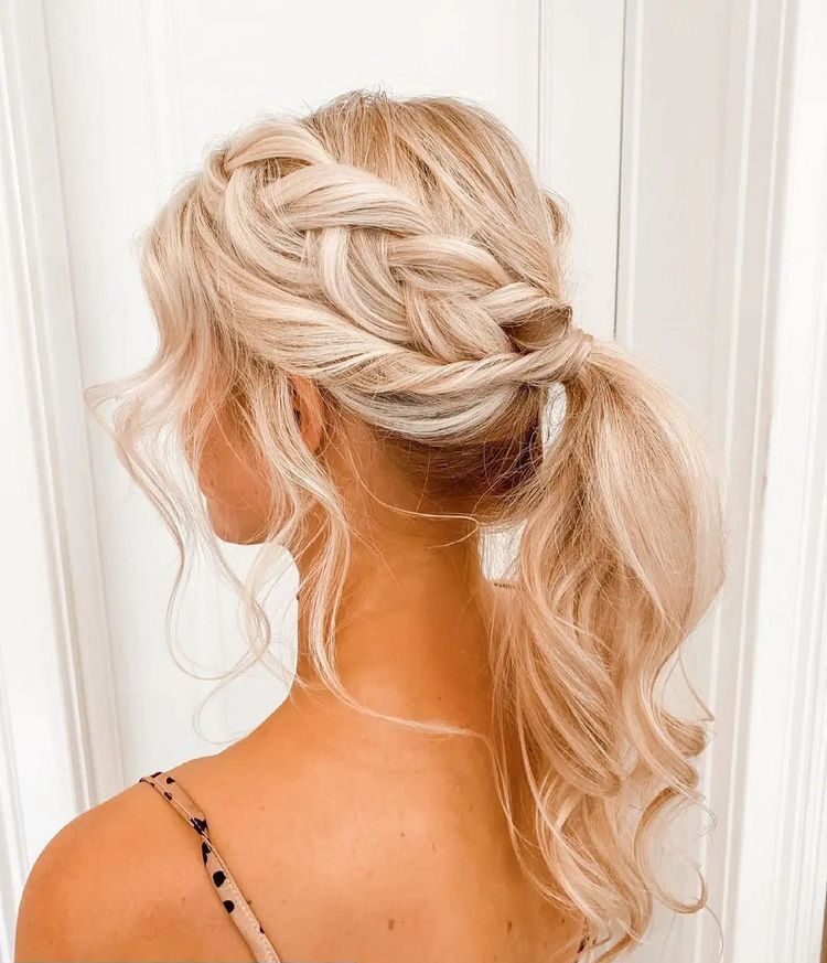 Light blonde hair styled into a thick Dutch side braid leading into a soft, wavy ponytail.