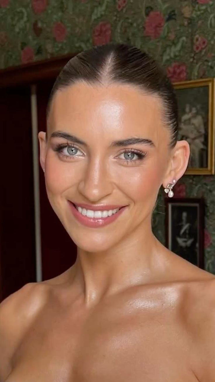 Brunette bride with a sleek bun featuring sculpted glowing cheekbones.