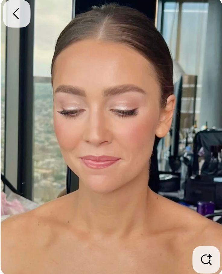 Shimmering champagne eyeshadow and a clean bun hairstyle for a wedding guest.