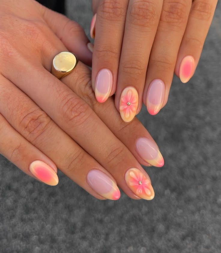 Soft almond shaped nails featuring a warm orange and pink aura gradient design with raised matte 3D flower accents on the ring fingers.