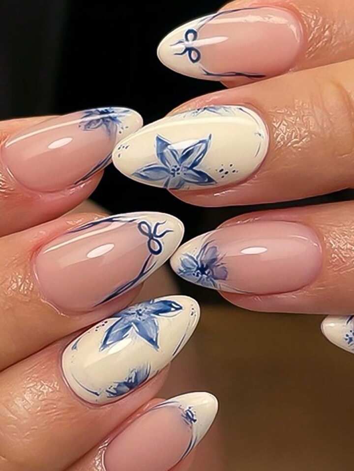 Square shaped nails with an ivory base decorated with intricate blue Mediterranean tile patterns and small blue bows.