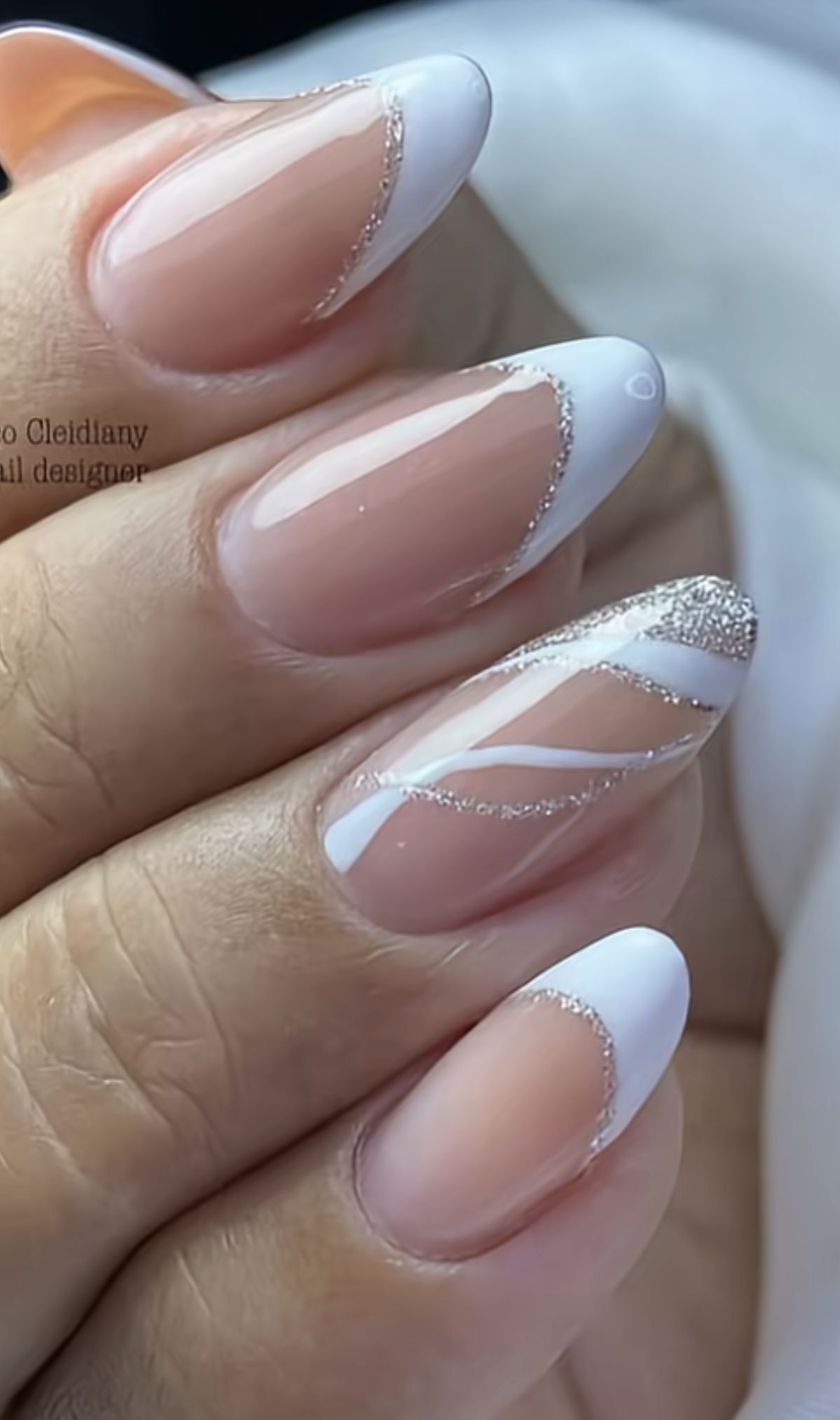 Oval nails with white French tips and sparkling silver wavy lines.