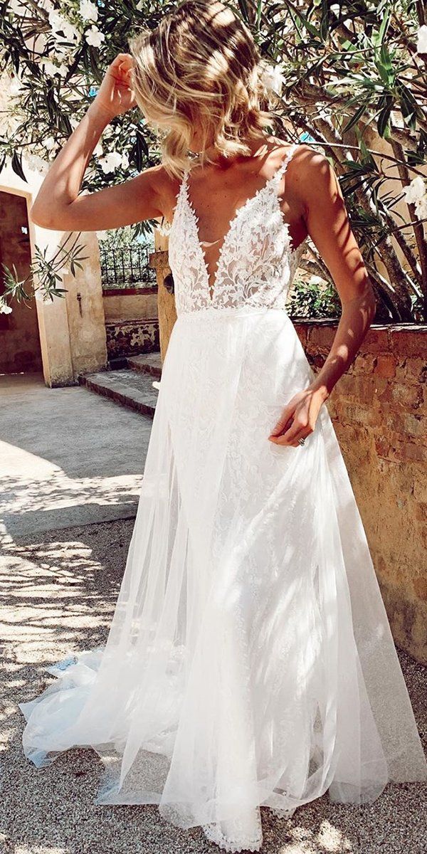 Bride outdoors wearing a wedding dress with a sheer lace botanical bodice and a floating tulle overlay skirt.