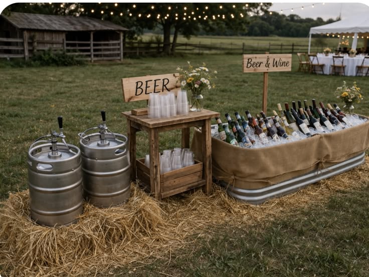 An outdoor wedding drink station featuring two metal beer kegs on straw bales next to a hessian-wrapped ice trough filled with bottles.