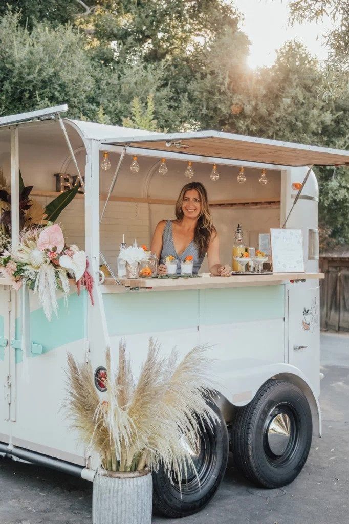 A mint and white vintage horse float decorated with dried florals, tropical flowers, and Edison lighting.
