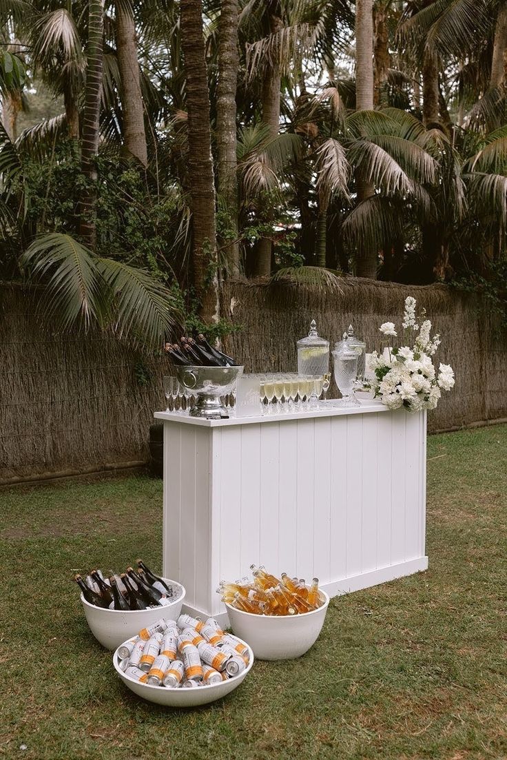 Minimalist white slatted bar with chilled drinks in white ice tubs sitting on the lawn in front
