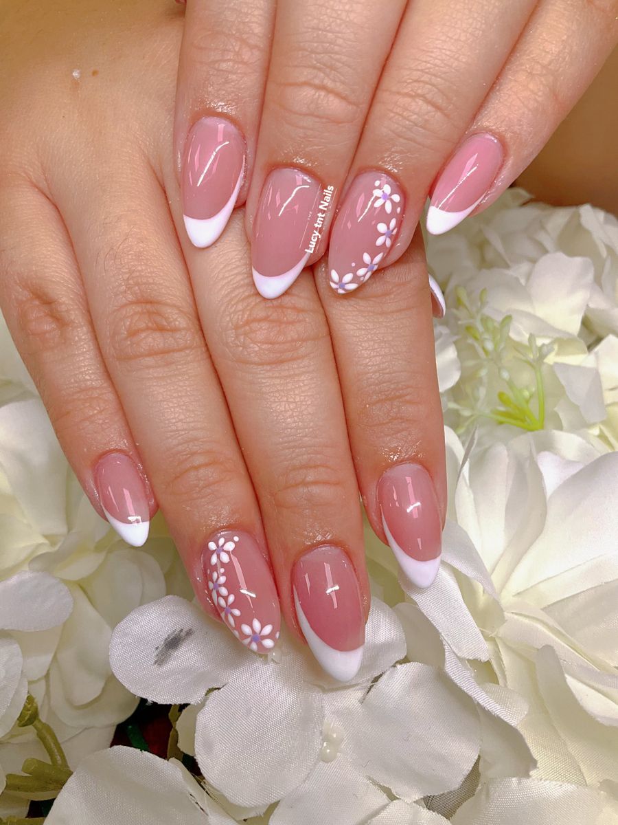 Extended almond nails with a white French tip and a trailing row of white garden daisies along the side.