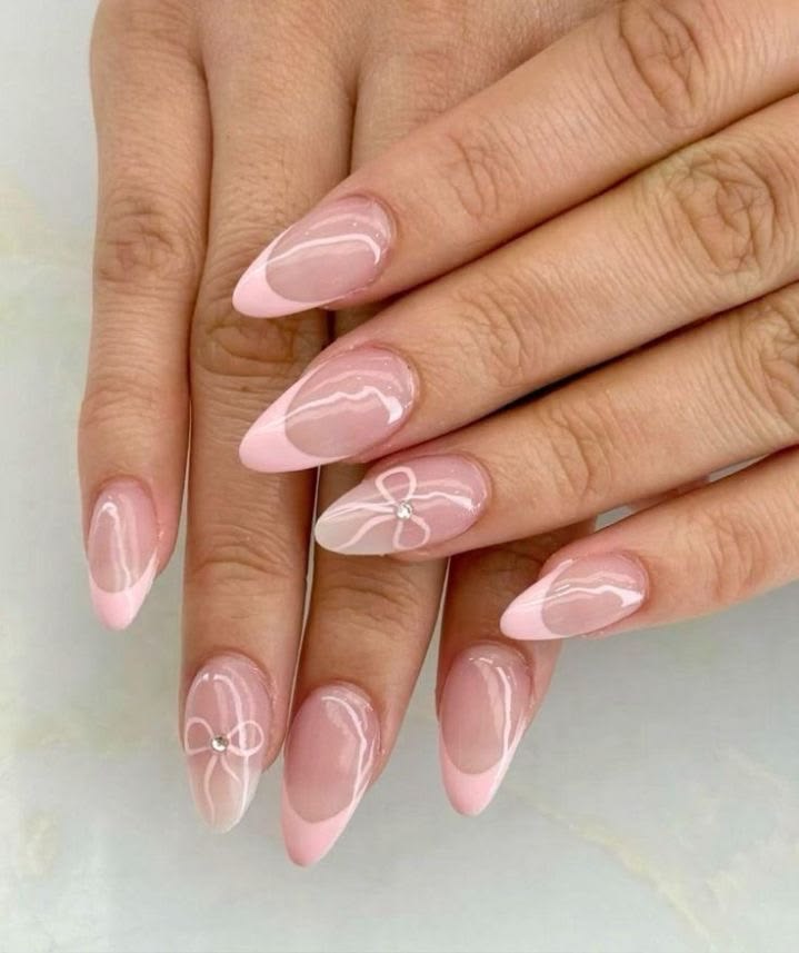 Soft pink French tip nails highlighted by delicate hand-painted white bow outlines and clear center rhinestones.