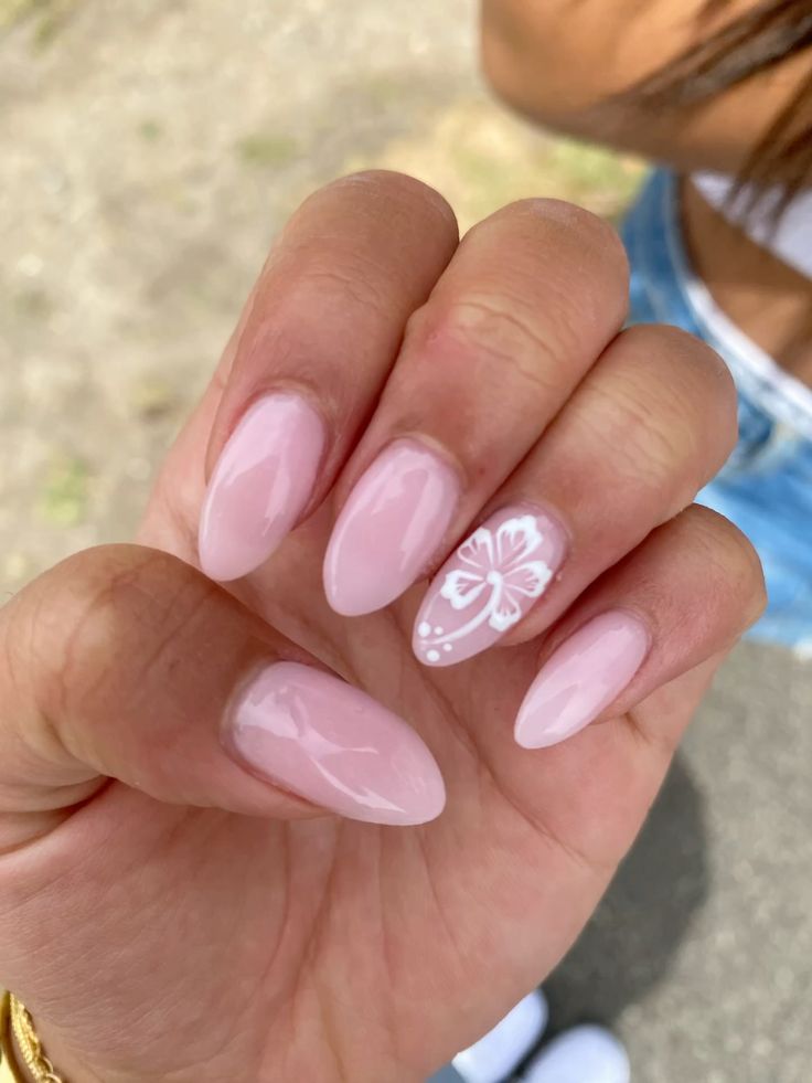 Glossy petal pink almond nails featuring a clean hand-painted white hibiscus accent outline.