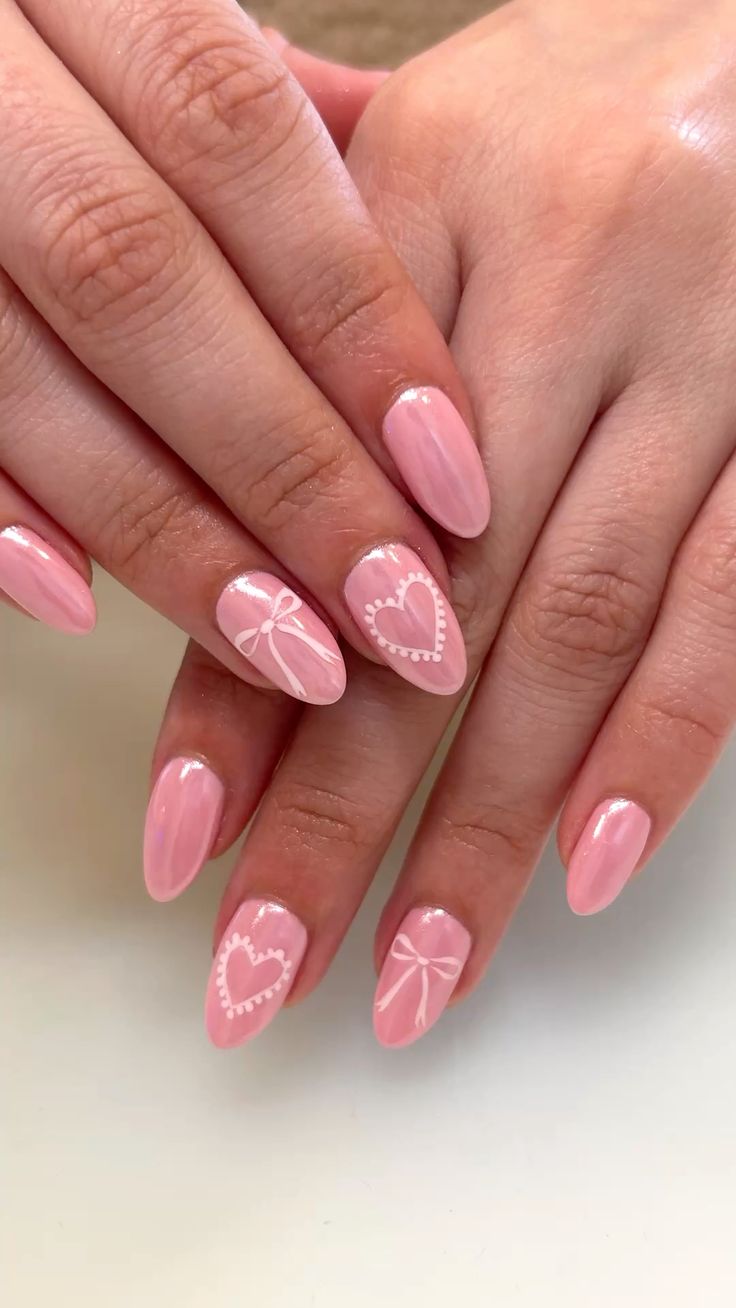 Glazed pink chrome nails detailed with delicate white hearts and daintily painted bows.