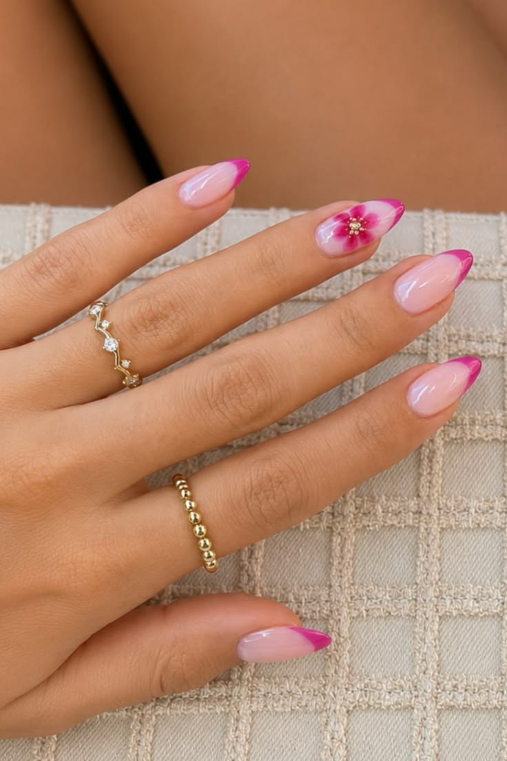 Long almond nails with fuchsia French tips and a watercolor floral accent, holding a textured purse.