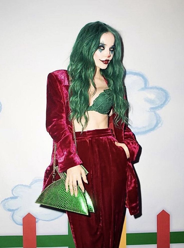 Woman wearing jewel-toned Joker Halloween makeup with teal eye diamonds, green hair and dark burgundy lipstick