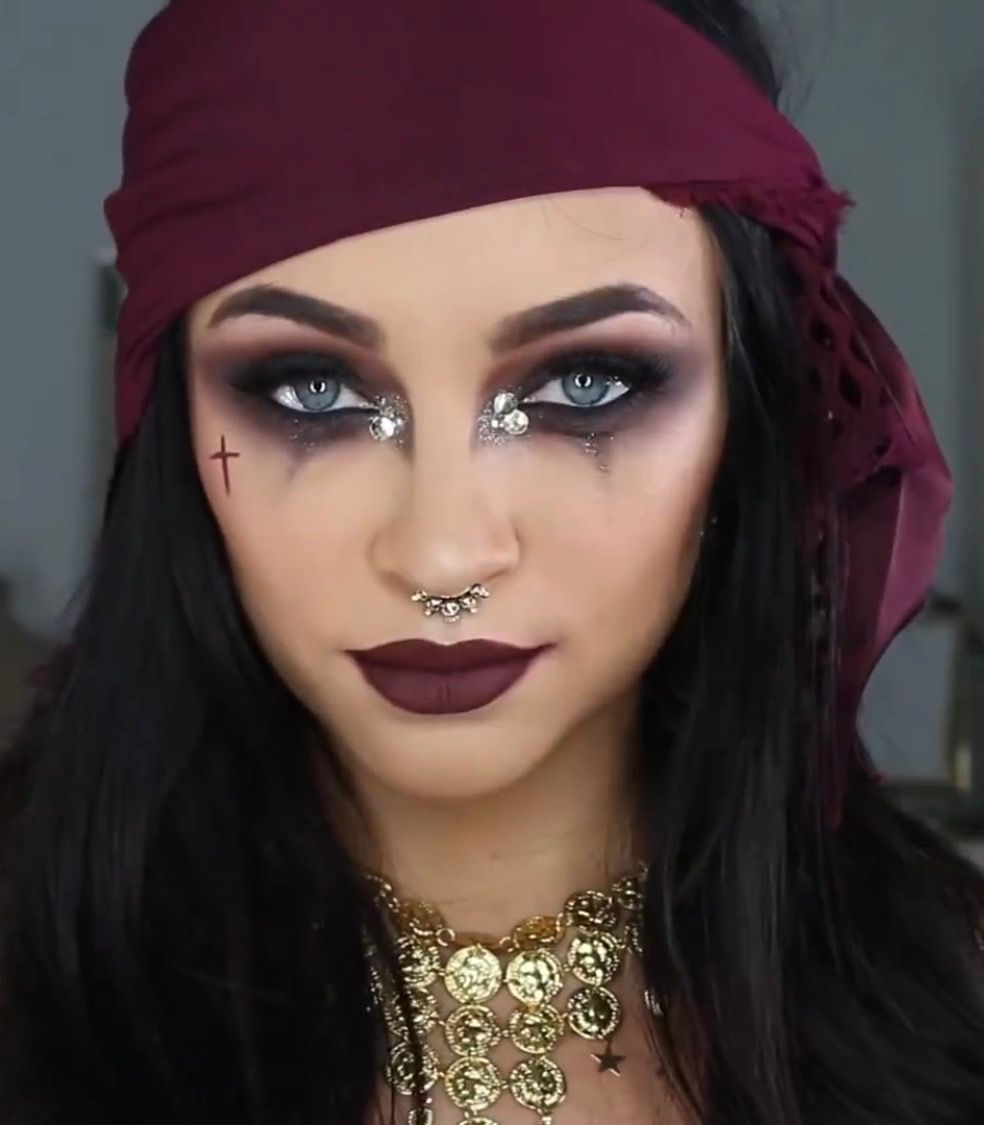 Woman wearing smoky Halloween makeup with silver rhinestones around her eyes and a deep wine-colored headscarf