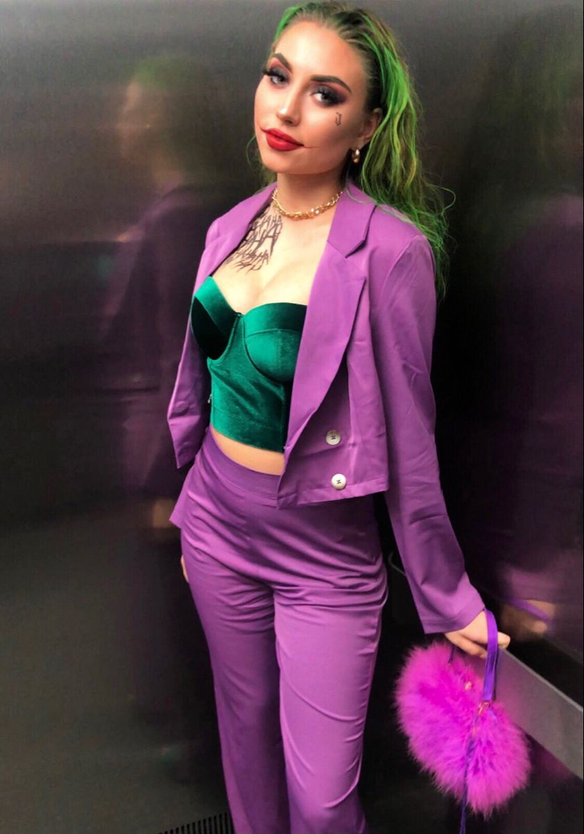 Woman wearing comic book villain Halloween makeup with green hair, bronze eyes and an exaggerated red smile