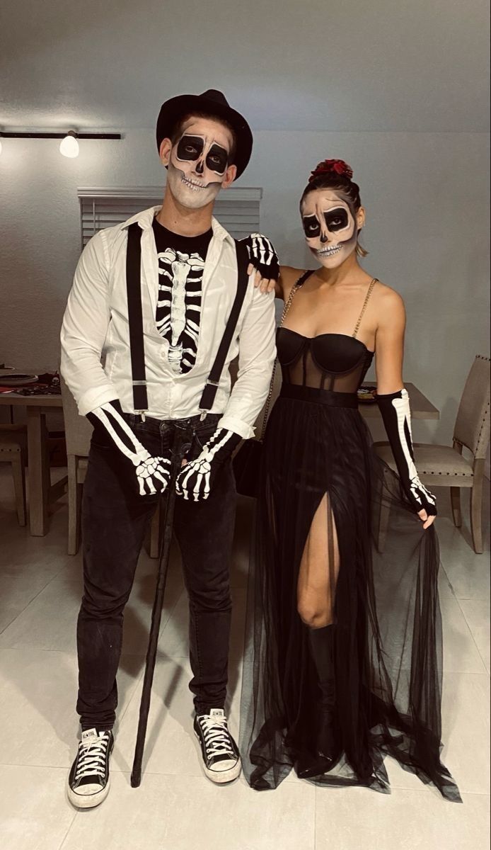 Couple wearing matching skeleton Halloween makeup with dark eye sockets, shaded cheekbones and skeletal smiles