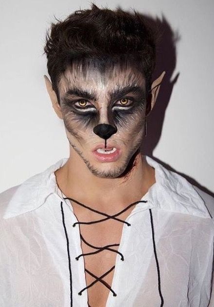 Man wearing realistic werewolf makeup with feathery facial fur brushstrokes and pointed ears 
