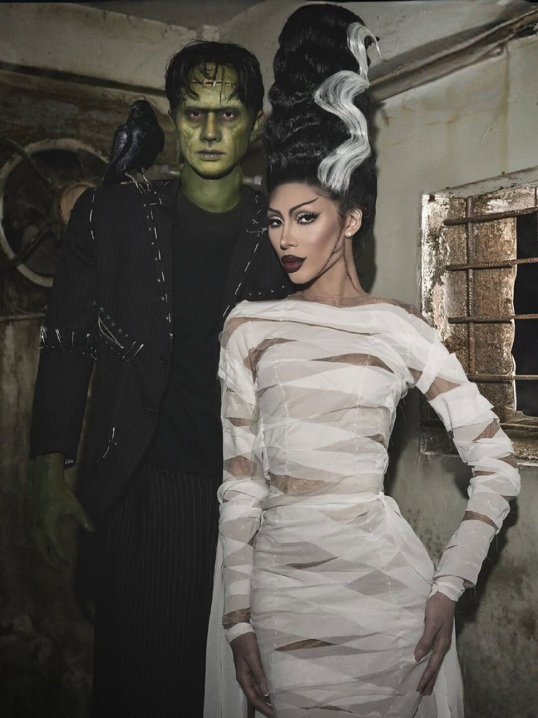 Woman with a high Bride of Frankenstein updo and white bandage dress beside a Frankenstein monster