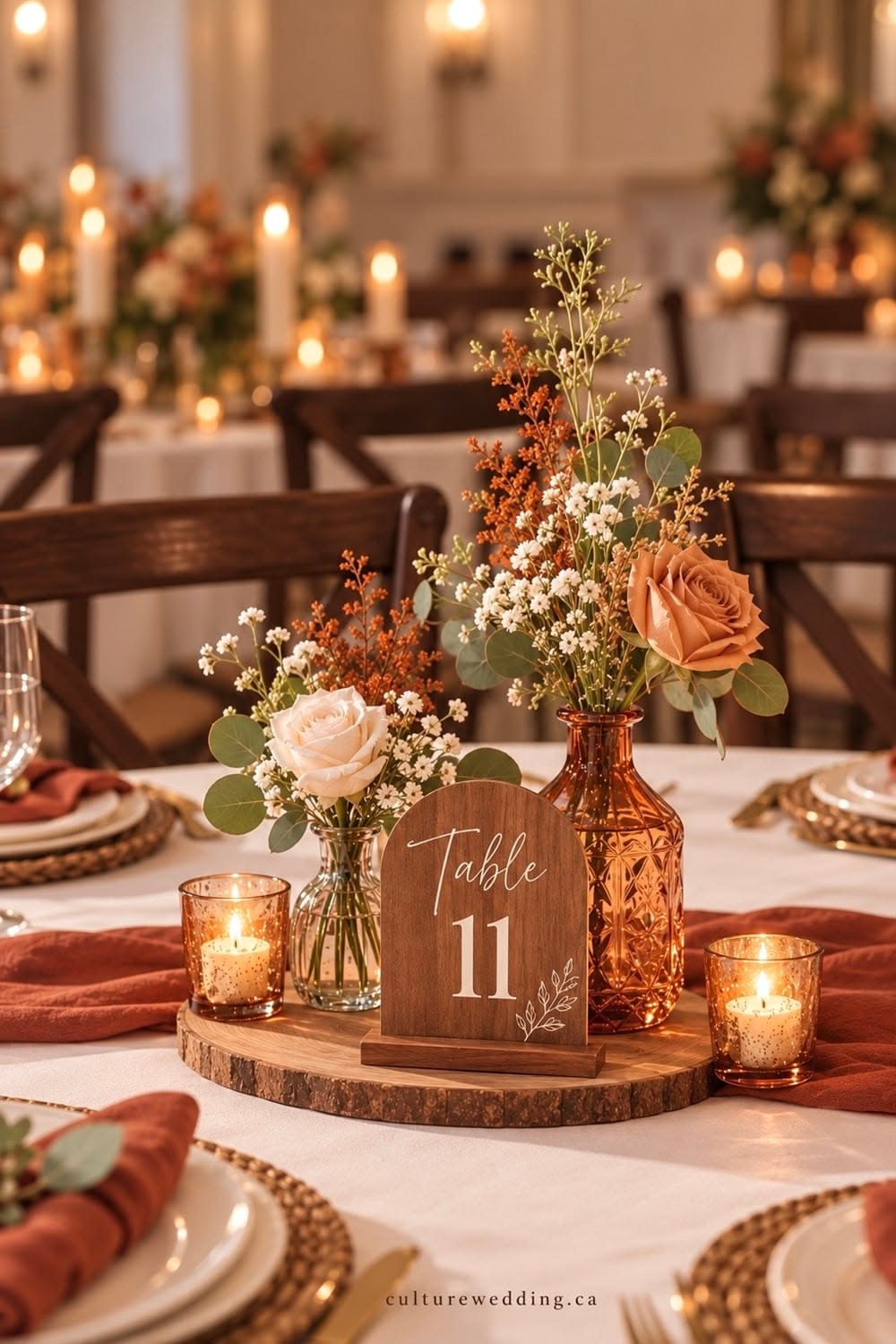 Wooden wedding table number 11 displayed with amber glass vases, peach roses, rust napkins and glowing votive candles.