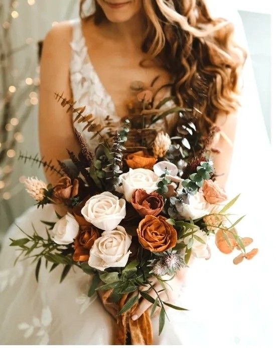 Bride holding a bridal bouquet of cream roses, rust flowers, eucalyptus, and dried grasses.