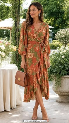 Woman wearing a rust and green floral long sleeve midi dress at a garden wedding setting
