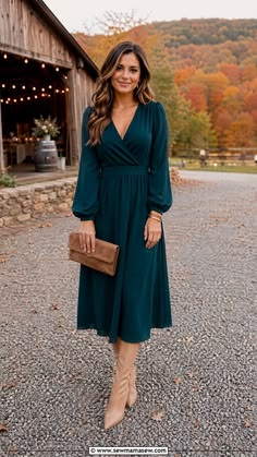  Woman wearing a deep teal long sleeve wrap midi dress at a fall barn wedding
