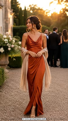 Woman wearing a rust satin draped dress with a soft shawl at an evening wedding
