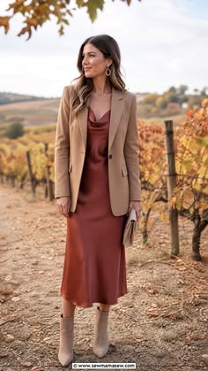 Woman wearing a berry satin slip dress with a tailored blazer at a vineyard
